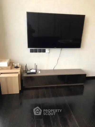 Modern living room with sleek TV setup and dark wood flooring, perfect for entertainment.