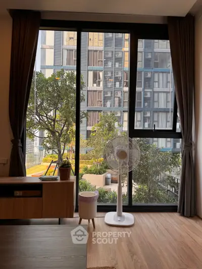 Modern apartment interior with large window and garden view, featuring stylish decor and natural light.