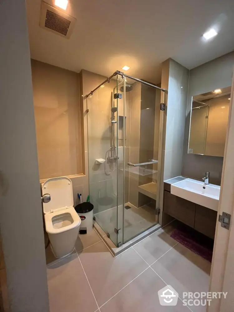 Modern bathroom with glass shower and sleek fixtures in contemporary home.