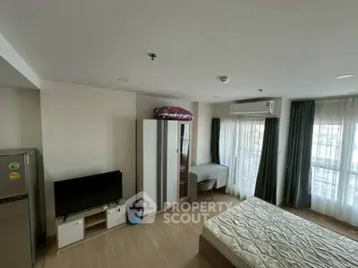 Modern bedroom with balcony, TV, and wardrobe in a bright apartment.