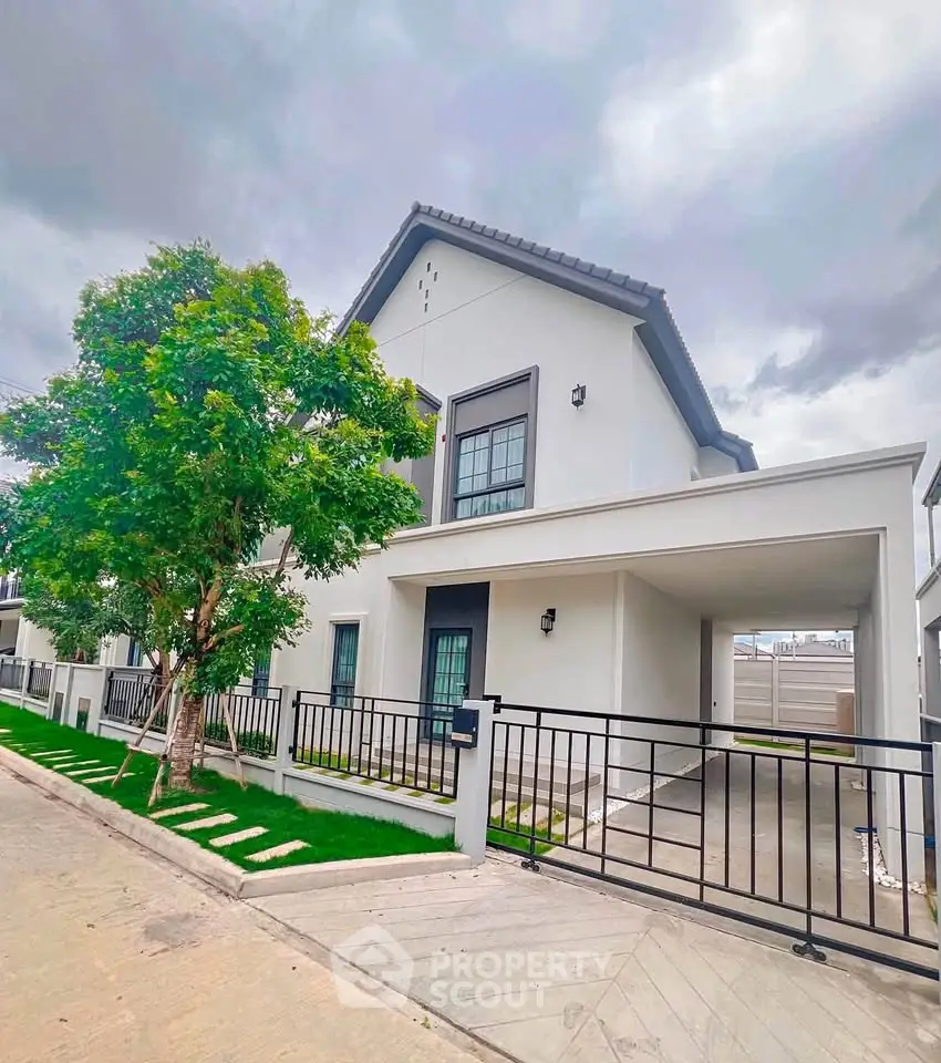 Modern two-story house with sleek design, spacious driveway, and lush greenery, perfect for family living.