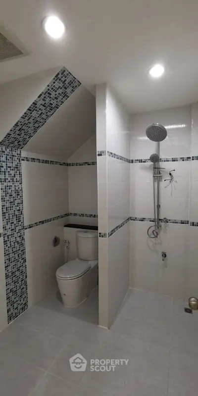 Modern bathroom with sleek shower and toilet, featuring stylish tile accents.