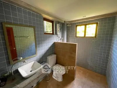 Spacious modern bathroom with blue tiles and natural light