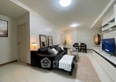 Spacious modern living room with sleek black sofa and elegant dining area, perfect for entertaining.