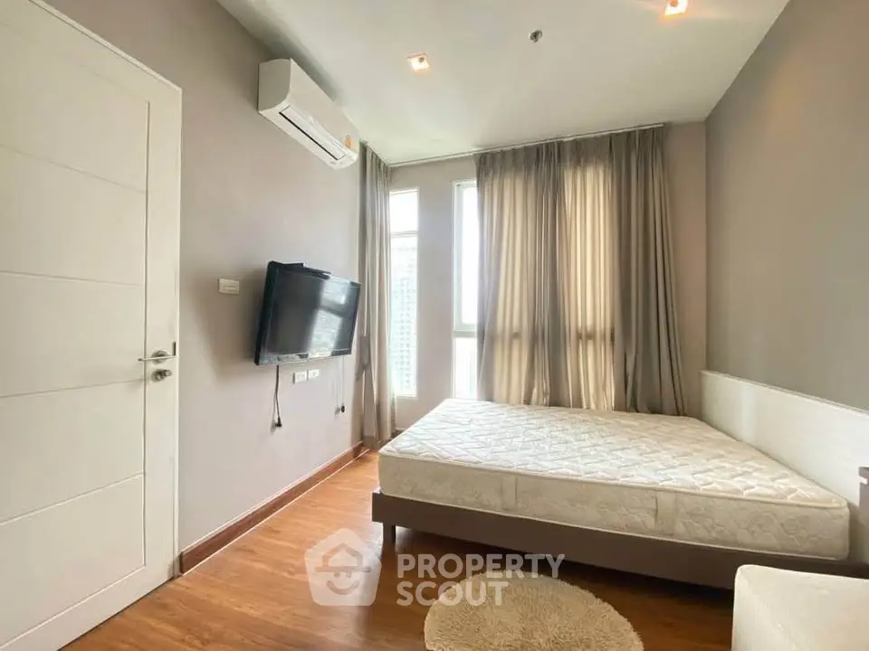 Modern bedroom with natural light, featuring a wall-mounted TV and air conditioning.