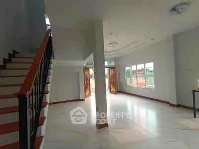 Spacious modern living room with elegant staircase and large windows