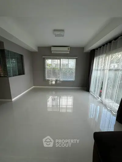 Spacious living room with large windows and modern air conditioning unit.