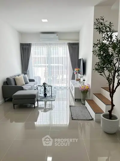 Modern living room with sleek design and natural light, featuring a cozy gray sofa and stylish decor.