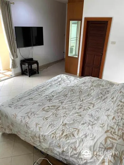 Spacious bedroom with modern TV and balcony access, perfect for relaxation and comfort.