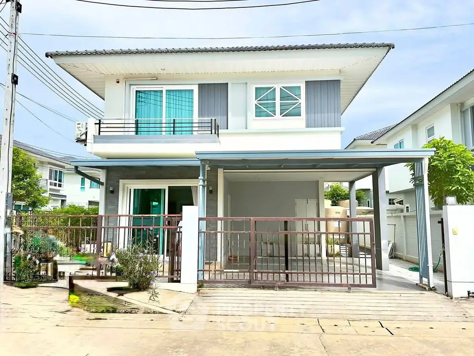 Modern two-story house with gated driveway and balcony in a suburban neighborhood.