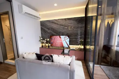 Modern living room with stylish decor and glass partition, featuring a cozy sofa and wall-mounted TV.