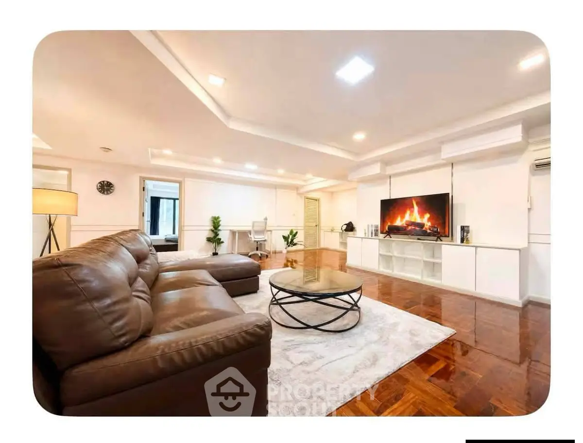 Spacious living room with modern decor and cozy fireplace, featuring a large leather sofa and elegant lighting.
