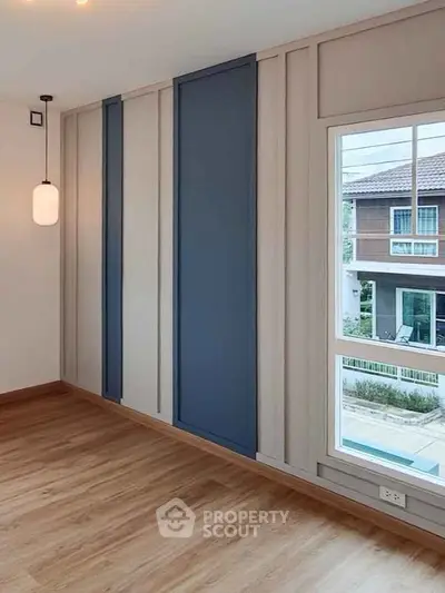 Modern interior with stylish wall paneling and large window offering a view of suburban neighborhood.