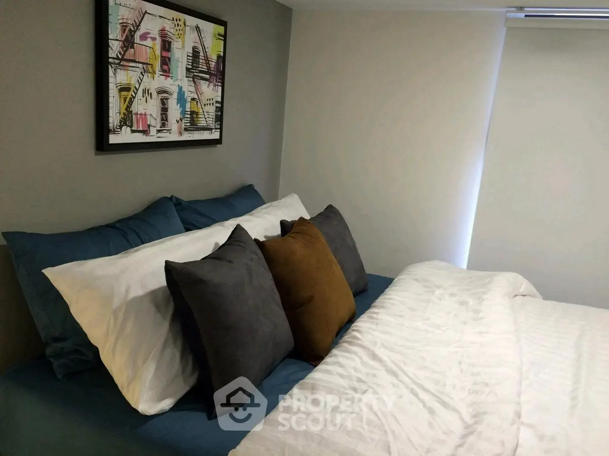 Cozy bedroom with modern art and plush pillows, perfect for relaxation and comfort.