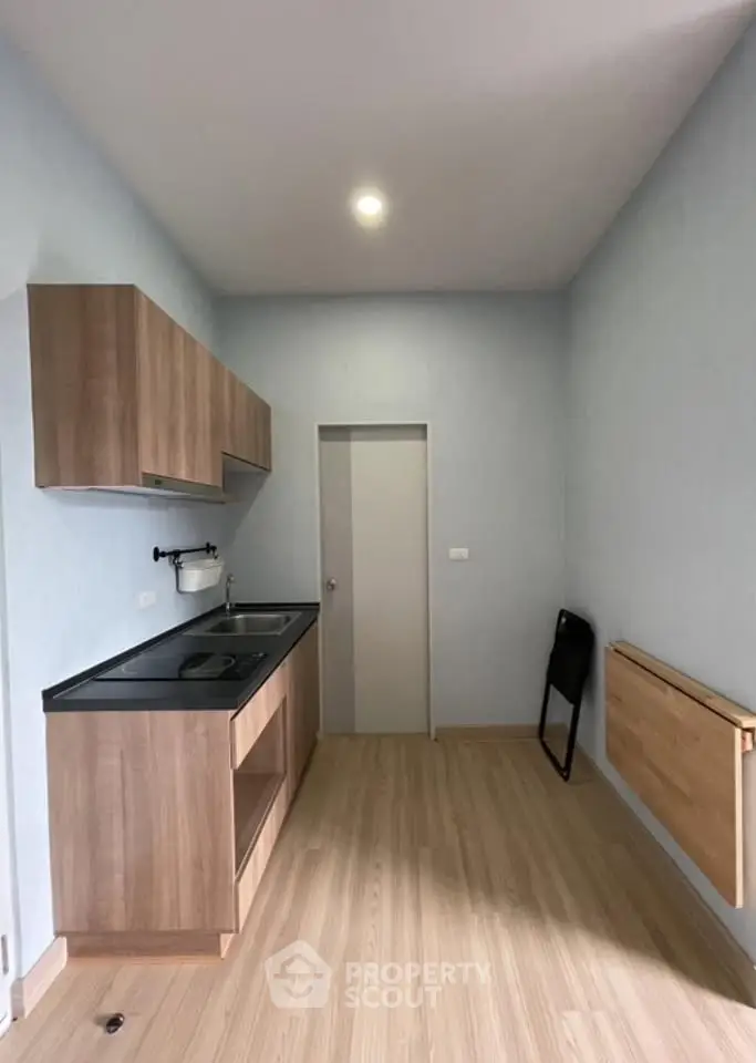 Modern minimalist kitchen with sleek wooden cabinets and foldable table.