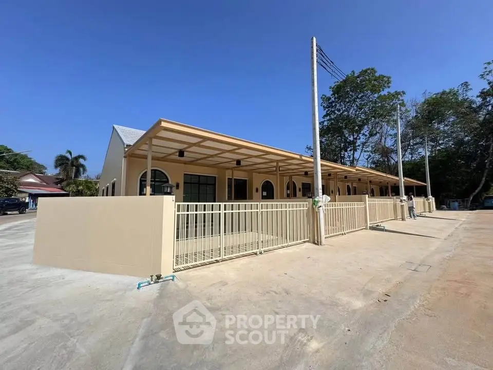 Modern single-story building with arched windows and spacious outdoor area under clear blue sky.