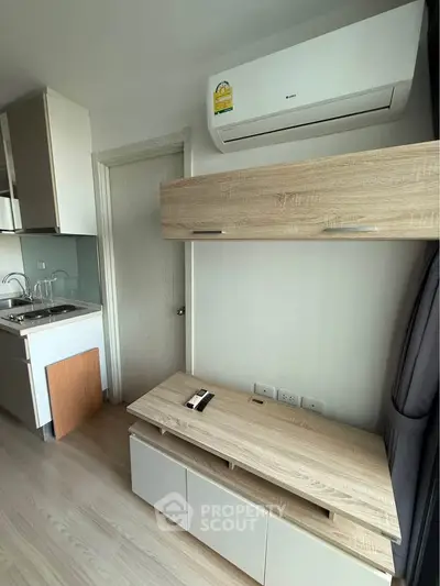 Modern apartment interior with sleek kitchen and air conditioning unit, showcasing compact and efficient design.