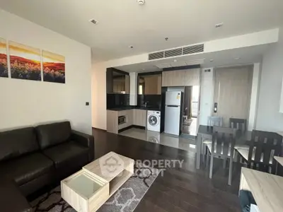 Modern open-plan living room with kitchen, featuring sleek furniture and appliances in a stylish apartment.
