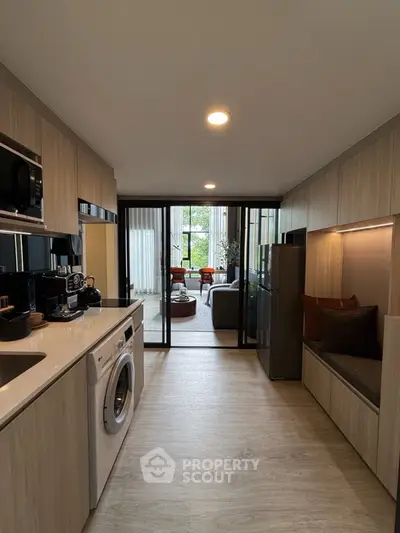 Modern kitchen with washing machine and open layout leading to stylish living room