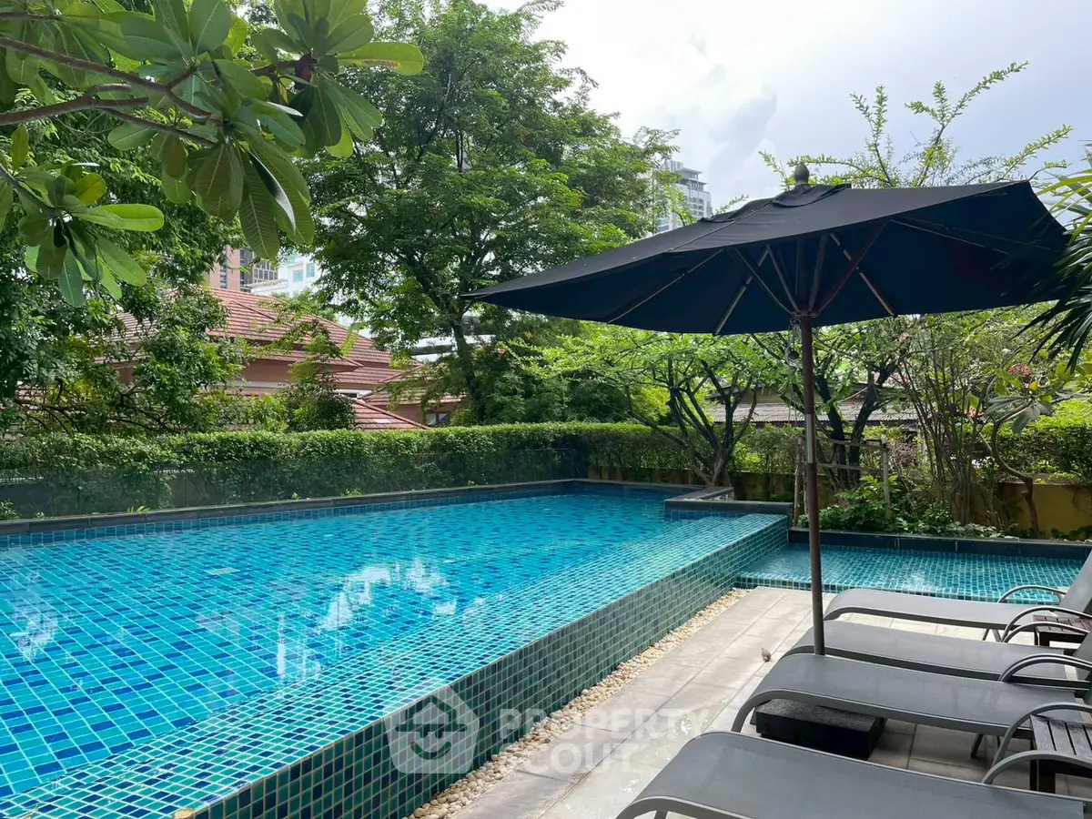 Luxurious outdoor pool area with sun loungers and lush greenery, perfect for relaxation.