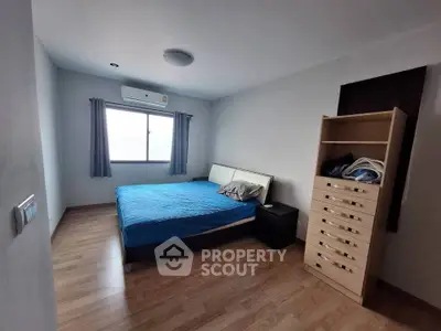 Spacious bedroom with wooden flooring and natural light