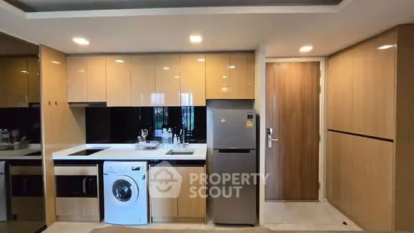 Modern kitchen with sleek cabinets, built-in appliances, and washing machine in stylish apartment.
