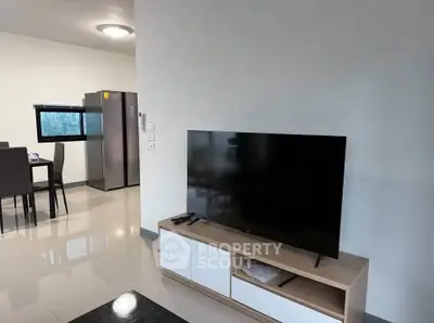 Modern living room with sleek TV and dining area, featuring contemporary furniture and bright lighting.