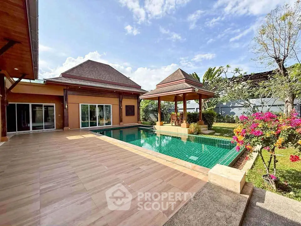 Luxurious villa with private pool and spacious patio, surrounded by lush greenery and vibrant flowers.