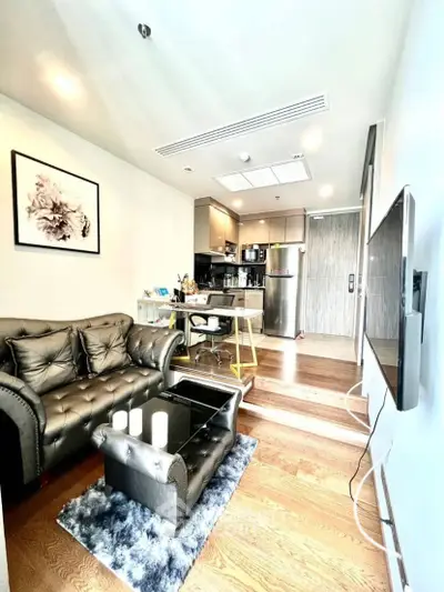 Modern living room with open kitchen, stylish decor, and cozy seating area.