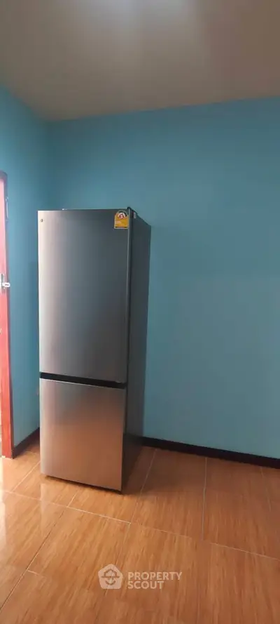 Modern kitchen with sleek stainless steel refrigerator and blue walls.