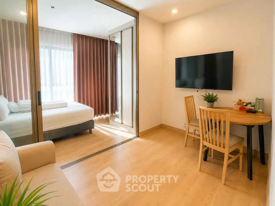 Modern apartment interior with cozy living area and bedroom, featuring wooden flooring and natural light.