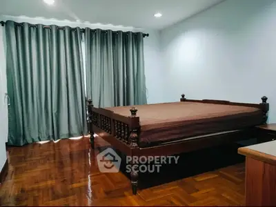 Spacious bedroom with elegant wooden bed and polished hardwood floors