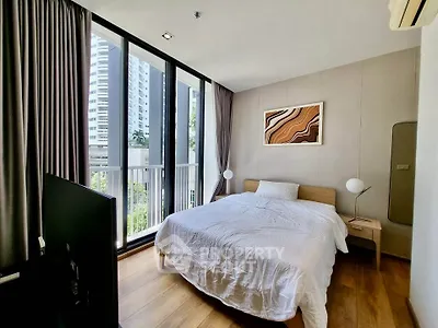 Modern bedroom with large windows and city view, featuring stylish decor and natural light.
