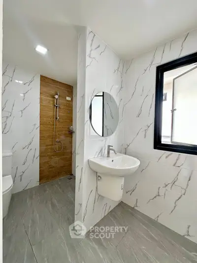 Modern bathroom with elegant marble tiles and round mirror