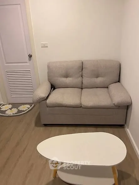 Cozy living room with beige sofa and modern coffee table in a compact space.