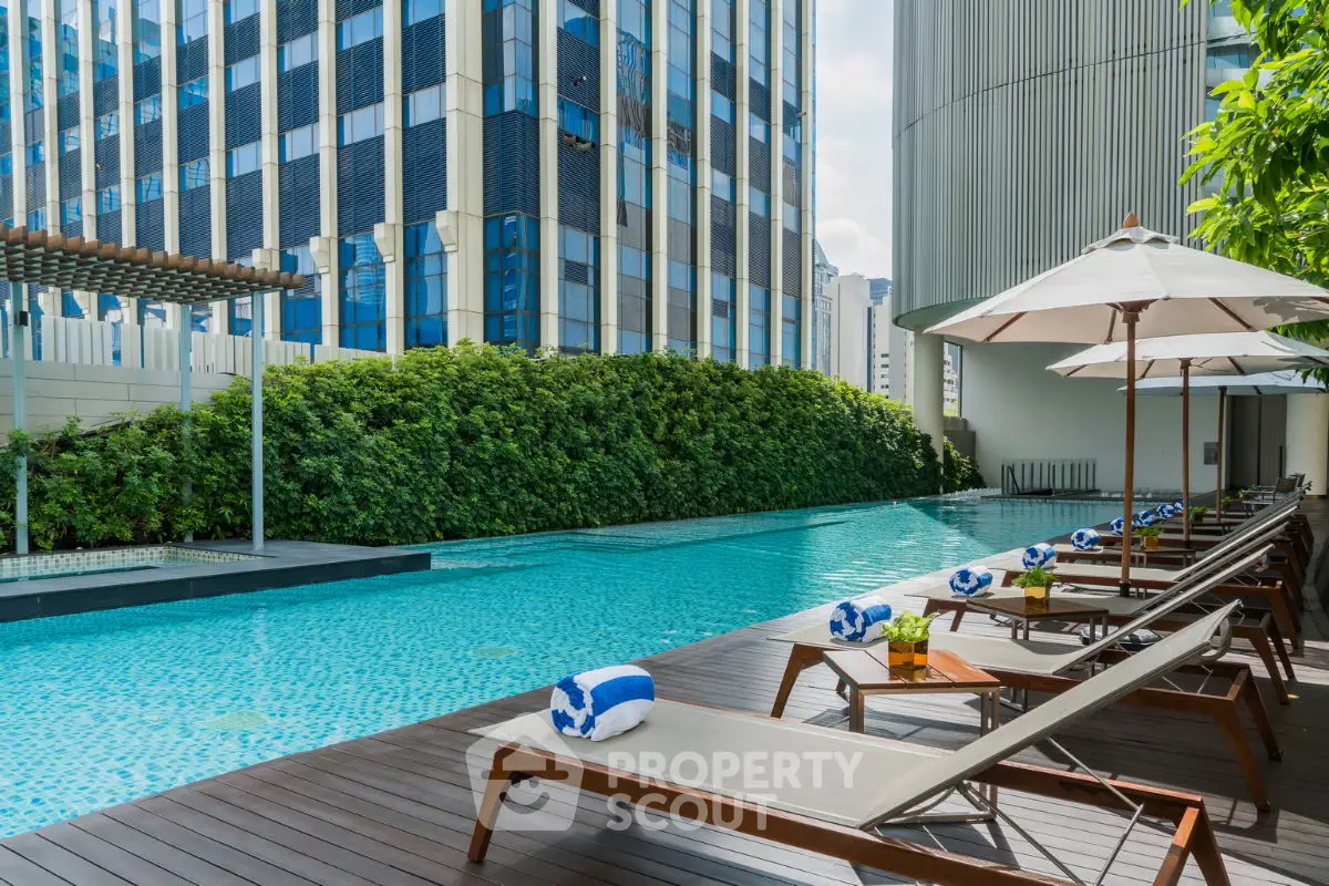 Luxurious rooftop pool with sun loungers and cityscape view, perfect for relaxation.