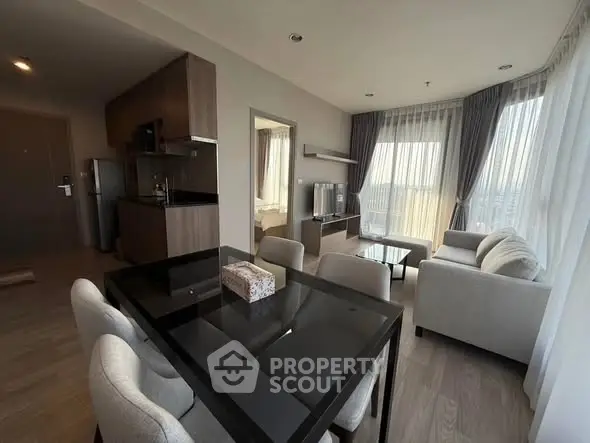 Spacious modern living room with open kitchen and dining area, featuring large windows and elegant furnishings.