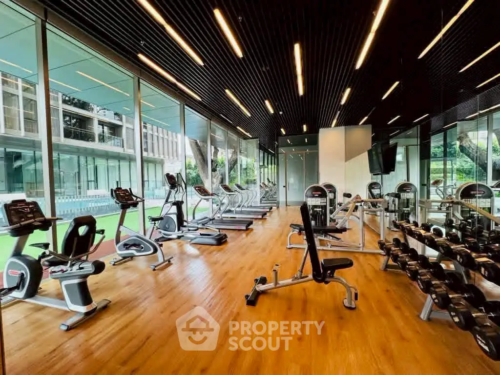 Modern gym with state-of-the-art equipment and floor-to-ceiling windows offering a lush garden view.