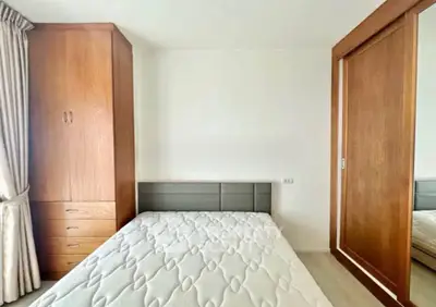 Modern bedroom with wooden wardrobe and cozy bed in bright apartment