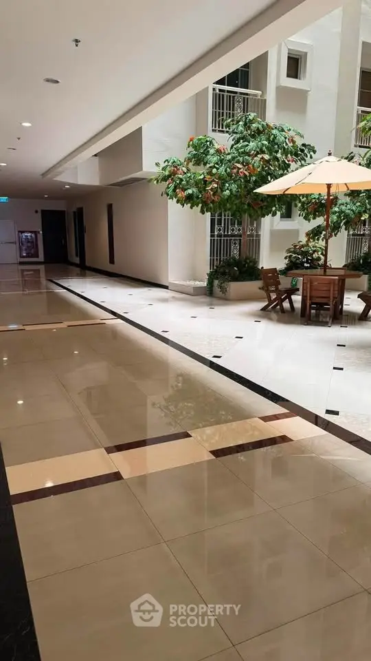 Elegant building corridor with seating area and indoor greenery, perfect for relaxation and socializing.