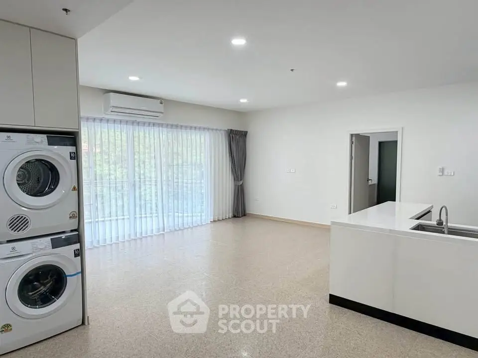 Spacious modern living room with laundry appliances and open kitchen layout