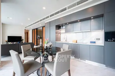 Luxurious modern kitchen with sleek cabinetry and elegant dining area in open layout apartment.