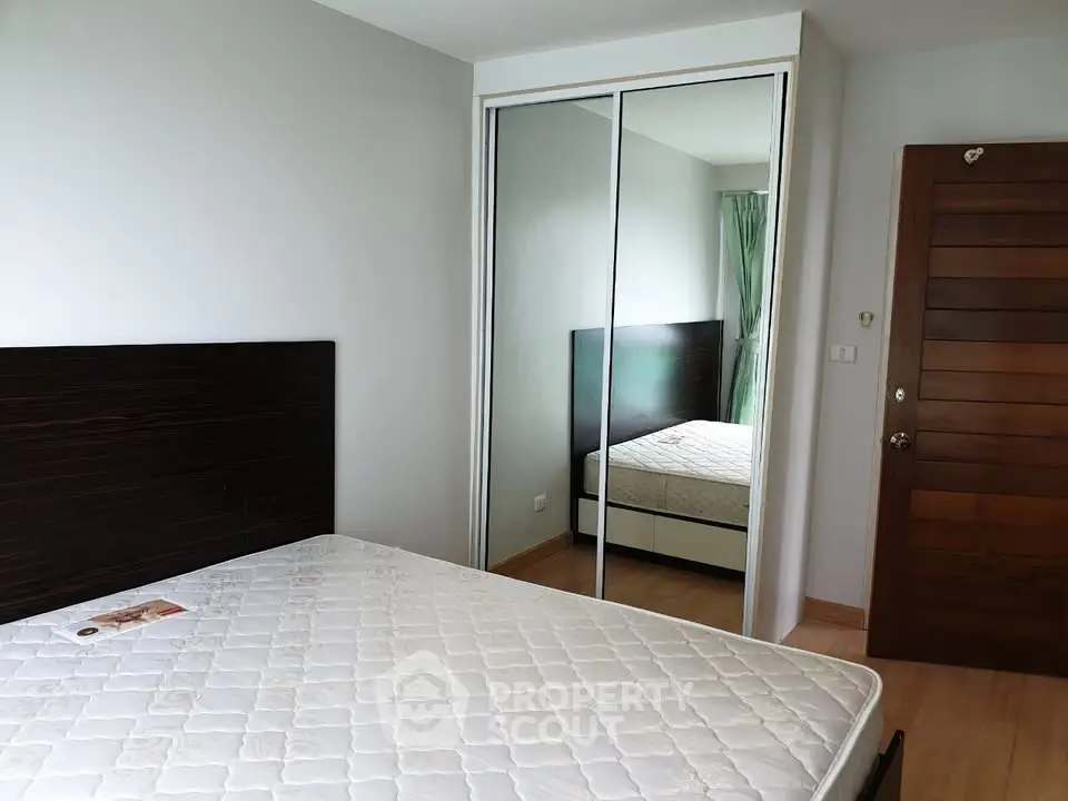 Spacious bedroom with mirrored closet and wooden accents, perfect for modern living.