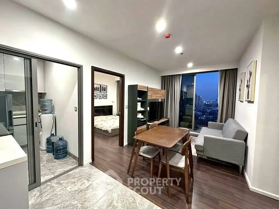 Modern apartment interior with open living and dining area, featuring city view and stylish furnishings.
