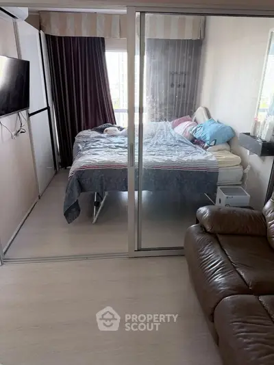 Cozy bedroom with glass sliding doors and modern furnishings in a well-lit apartment.