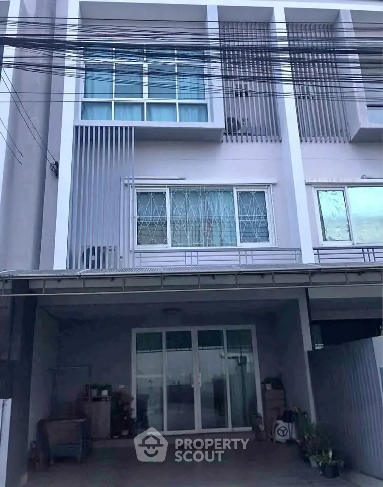 Modern townhouse exterior with large windows and covered parking area.