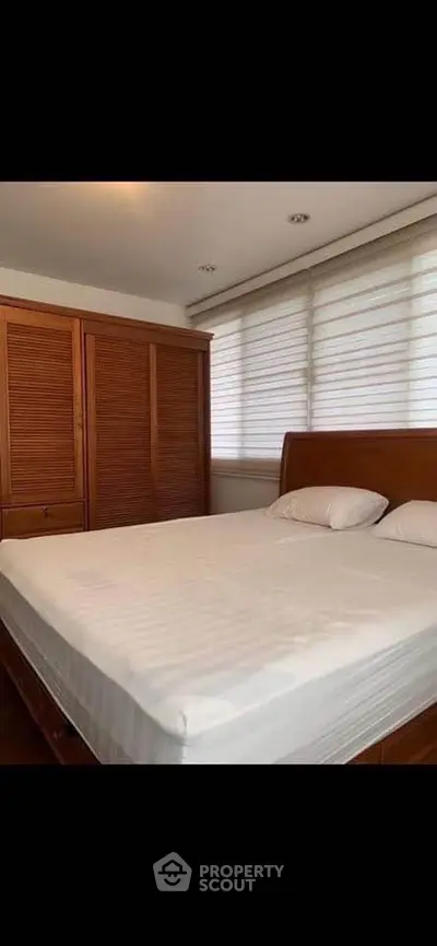 Spacious bedroom with wooden wardrobe and large bed, perfect for comfort and relaxation.