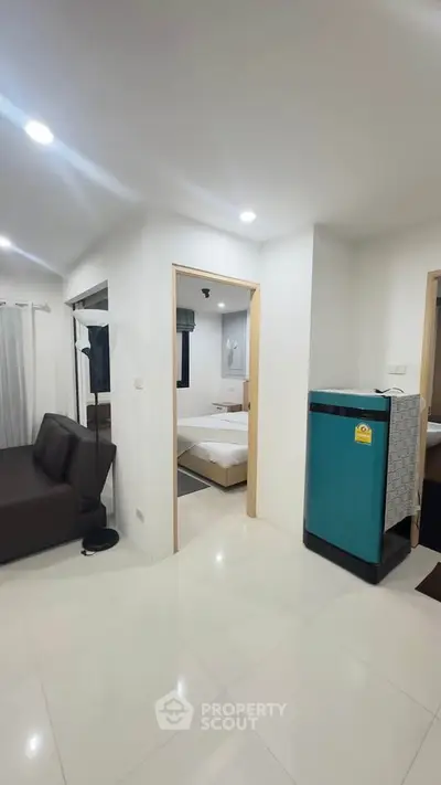 Modern apartment interior with living room and bedroom, featuring sleek furniture and bright lighting.