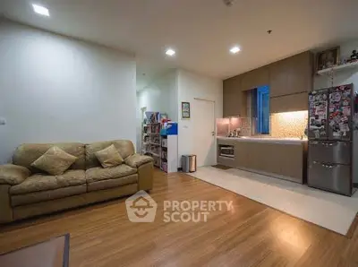 Modern open-layout living room with cozy sofa and sleek kitchen area.