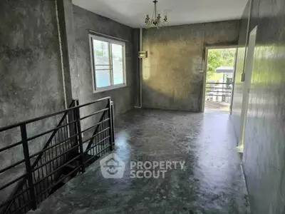 Spacious industrial-style interior with polished concrete floors and large window.